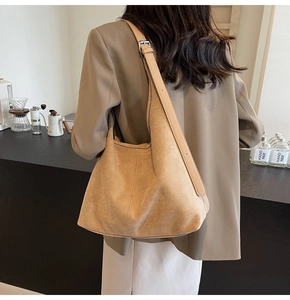 Close-up of brown suede bucket bag with leather strap and silver buckle on a model