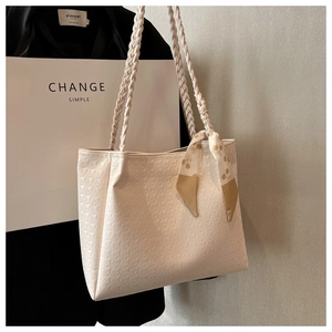 Detail of cream tote bag featuring geometric patterns and a floral silk scarf handle