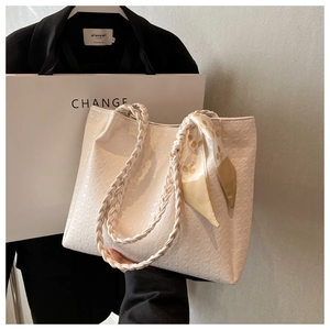 Detail of white tote bag featuring houndstooth texture and woven handle with silk scarf