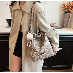 Detail of canvas bucket bag with brown geometric stripes and plush monster charm