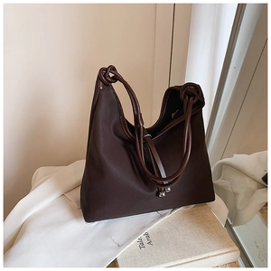 Detail of dark brown tote bag with rope knot strap and metallic bead accents