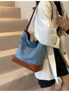 Minimalist denim and brown leather bucket bag shown as a spacious shoulder tote