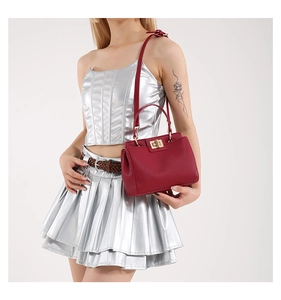 Detail of burgundy lychee grain leather bag with golden twist lock and thin handle
