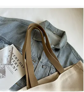 Detailed stitching and thick brown handle connection on cream canvas tote bag