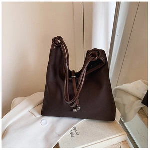 Detail of dark brown tote bag with woven handles and decorative silver metallic beads