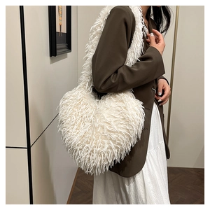Détail de la texture d'un sac à bandoulière en fausse fourrure blanche en forme de cœur