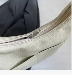 Detailaufnahme des silbernen Reißverschlusses und der Lederstruktur der beigen Tasche