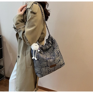 Close-up of geometric striped canvas tote with metal chain strap and plush pendant