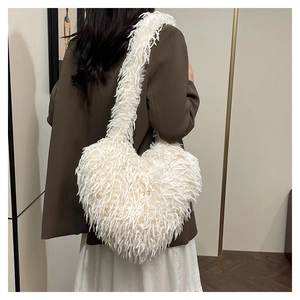 Détail du sac à épaule cœur en fausse fourrure blanche sur un blazer de couleur foncée