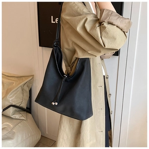 Detail view of black tote bag featuring elegant knotted straps and silver bead drawstring