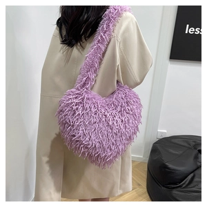 Détail d'un sac à bandoulière en peluche violette en forme de cœur porté par un mannequin