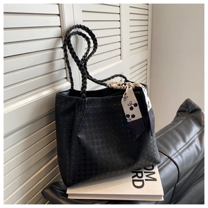 Detail of black houndstooth tote bag with woven handle and silk scarf accessory