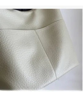 Detailaufnahme der hochwertigen Lederstruktur und der feinen Nähte an der beigen Beuteltasche