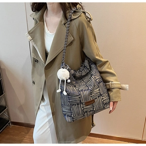 Detail of blue and white striped canvas bucket bag with chain strap and plush pendant