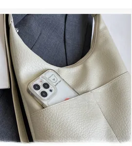 Detail der Außentasche der beigen Beuteltasche zeigt Platz für ein großes Smartphone