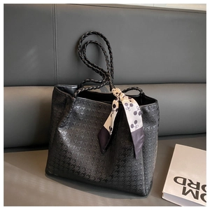 Close-up of textured black tote bag with braided handles and decorative silk scarf