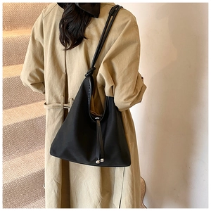Detail of black tote bag with knotted shoulder strap and silver metal ball drawstring