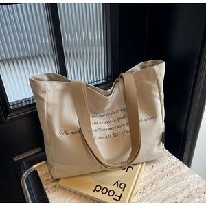 Close-up of minimalist off-white canvas tote bag on marble table with sunlight text