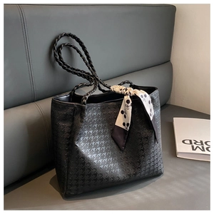 Detail of black embossed tote bag with woven handles and decorative printed silk scarf