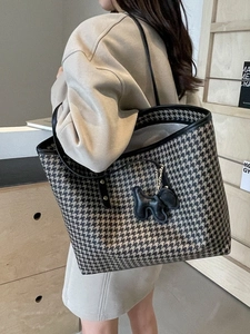Chic houndstooth tote bag with leather straps and dog charm worn over the shoulder