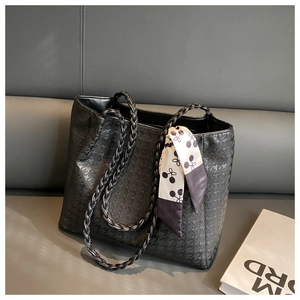 Detail of black tote bag featuring star pattern texture and woven leather handles