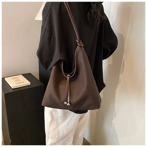Detail shot of a dark brown matte leather tote bag with stylish metallic ball pendants