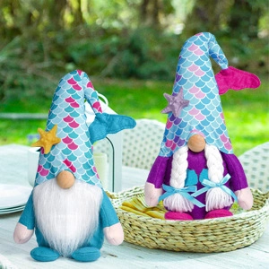 Gnomi sirena blu e viola con cappelli a coda di pesce su un tavolo di legno all'aperto