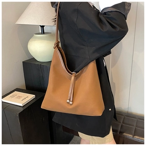 Detail of a large brown hobo bag with a decorative knot strap and metallic ball accents