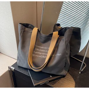 Detail of dark grey canvas tote bag with khaki straps and elegant white script print