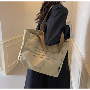 Close-up of khaki canvas tote bag featuring graphic print and reinforced shoulder strap