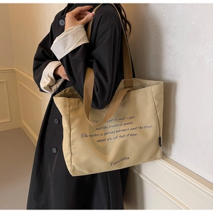 Detail of khaki canvas tote bag with dark brown straps and artistic print design