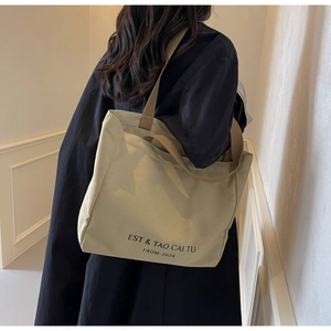 Detail of canvas tote bag showing thick webbing strap and minimalist graphic print