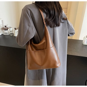 Detailansicht einer braunen Eimer-Tasche aus Leder mit Narbenstruktur an einem Modell