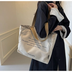 Detail of minimalist canvas tote bag with brown shoulder straps and poetic text print