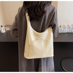 Detail der cremefarbenen Lederstruktur einer minimalistischen Hobo-Schultertasche mit Platz
