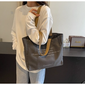 Close-up of a large grey canvas tote bag with khaki straps and motivational text