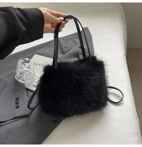 Close-up of fluffy black faux fur tote bag with leather straps on a grey blazer