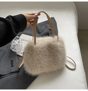 Detail of soft cream faux fur handbag with brown leather strap held by a model