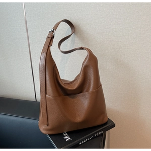 Detail einer braunen Eimer-Tasche aus Leder mit Lychee-Muster und Silber-Schnalle