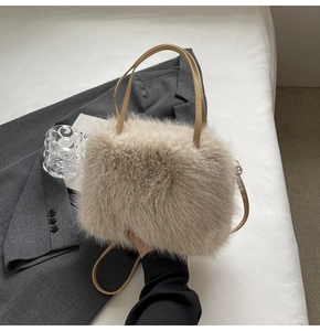 Detail of beige faux fur handbag showing fluffy texture with grey blazer and handle