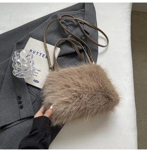 Detail of light brown faux fur handbag on grey suit with gold hardware and strap