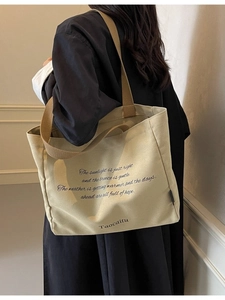 Minimalist beige canvas tote bag with brown straps shown on a model's shoulder