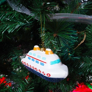 Kerstboomversiering in de vorm van een cruiseschip hangend aan een dennentak