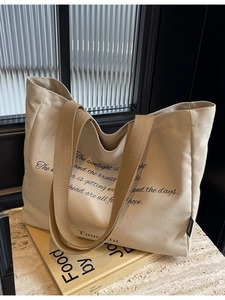 Minimalist canvas tote bag with black typography and wide khaki shoulder straps for women