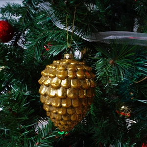 Golden pinecone Christmas tree ornament hanging on a festive green branch