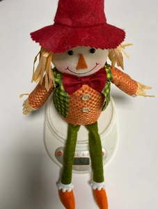 Detail showing the weight of the sitting scarecrow doll on a digital scale