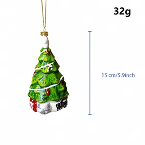 Dettaglio di un addobbo natalizio a forma di albero verde con trama neve e base regalo