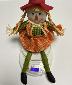 Detail shot of a sitting autumn scarecrow doll showing weight on a digital scale