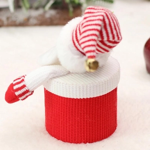 Detail of red knit Christmas candy jar with striped mini hat and gold bell on white plush