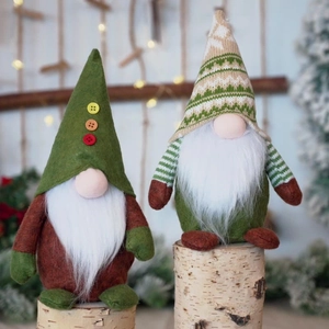 Detail of Christmas gnomes with green knitted hats on birch logs with bokeh lights